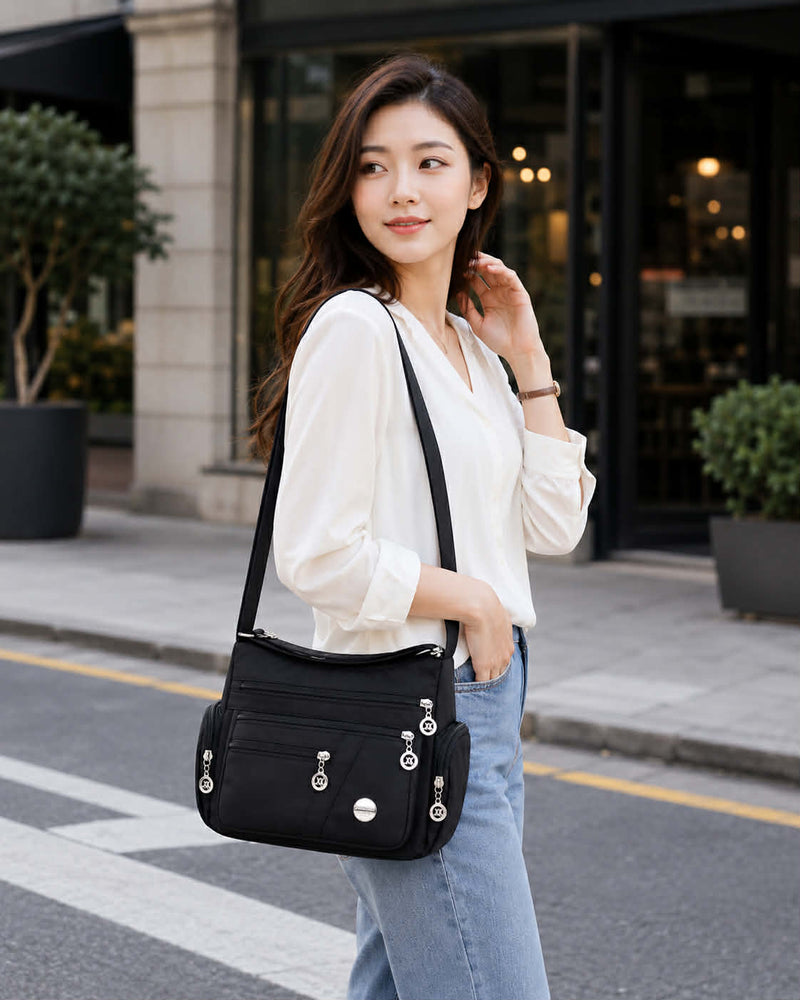 Women’s black nylon crossbody messenger bag worn by model in urban street setting
