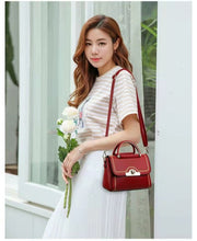 Woman carrying a red structured crossbody handbag with gold-tone handle and elegant detailing.
