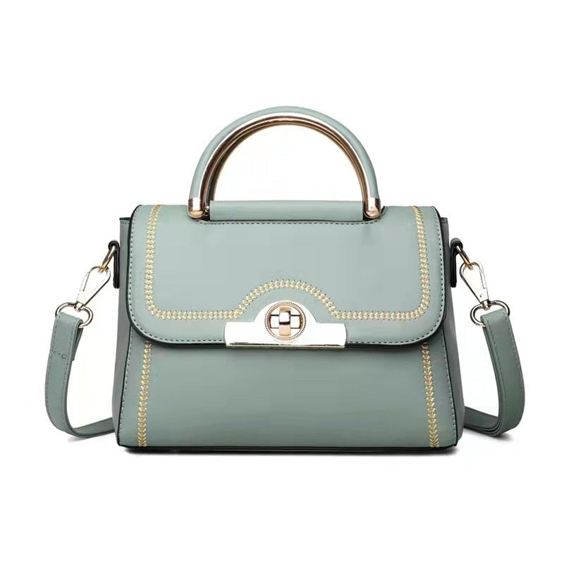 Sky blue structured crossbody handbag with gold-tone handle and elegant detailing.
