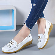 Woman wearing white genuine leather slip-on loafers with casual everyday outfit.

