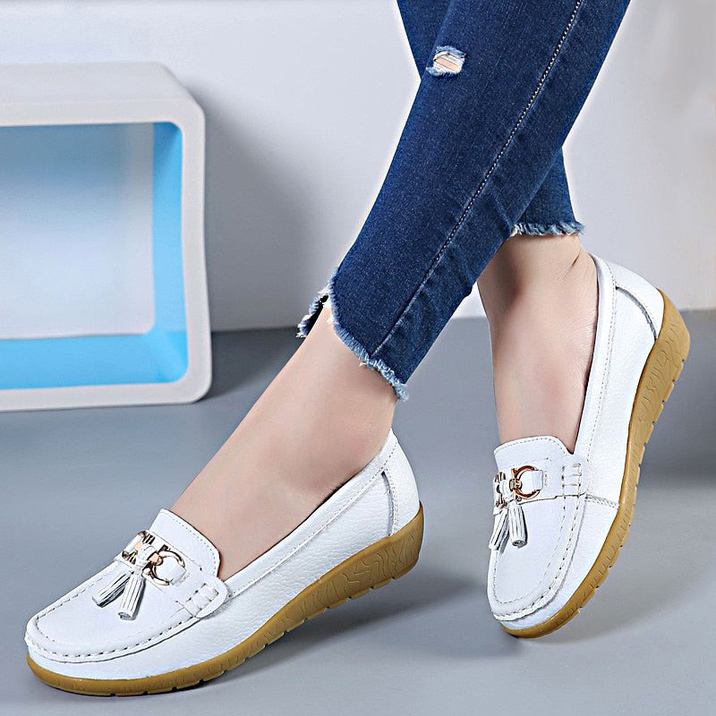 Woman wearing white genuine leather slip-on loafers with casual everyday outfit.
